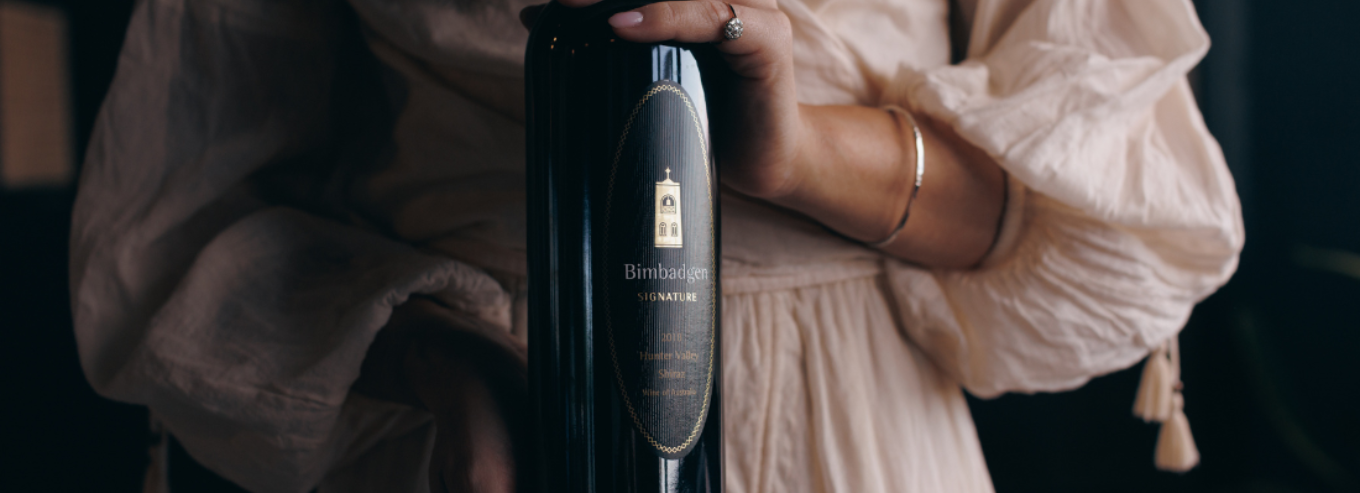 A woman holding a bottle of Bimbadgen Signature shiraz